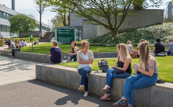 Students sitting on the wall outside a lecture theatre