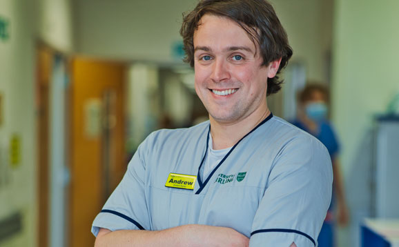 Andrew, a proud nursing student, standing with his arms folded