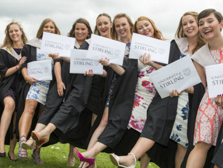 group of girls in graduation gowns and holding their certificates 