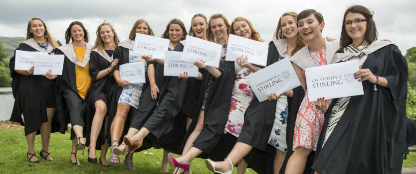 group of girls in graduation gowns holding their certificates 
