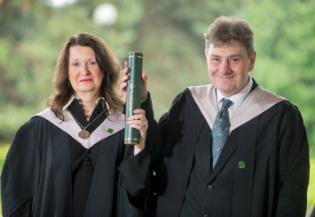 a man and woman standing together smiling both holding a degree 