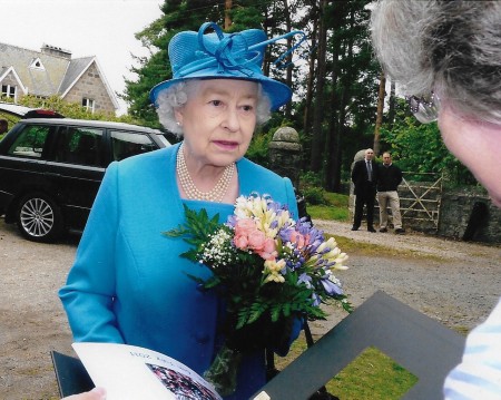 The Queen being offered flowers and a book