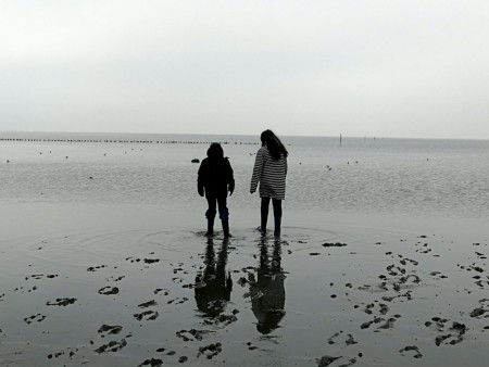 Two people standing looking out to sea