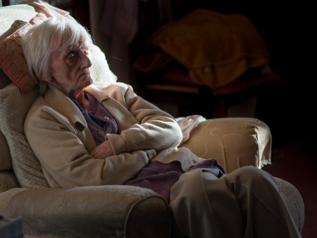 An elderly lady sitting in the dark