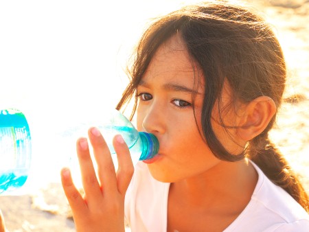 Child drinks from a bottle of water