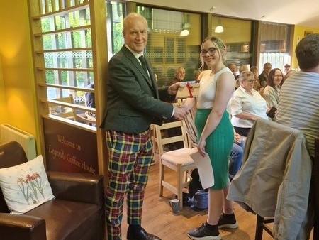 Winner Sam Nimmo receives her prize from the Buchanan of Buchanan, Mike Buchanan at the Legends Cafe event