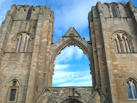 A coloured photograph of Elgin Cathedral showing a large arched glass-less window
