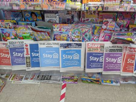 Newspaper shelves in a newsagents in May 2020 showing headlines including 'Stay Home!'