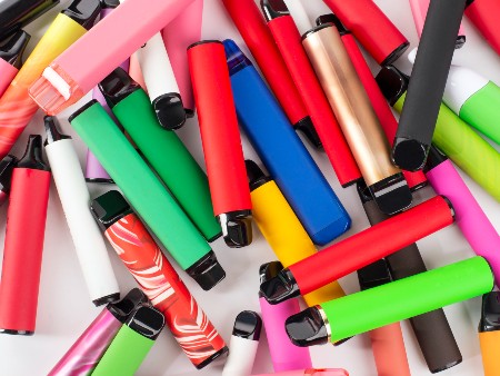A pile of brightly coloured e-cigarettes scattered across a surface