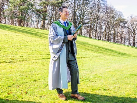 Dougie Vipond poses with his degree on the University of Stirling campus.