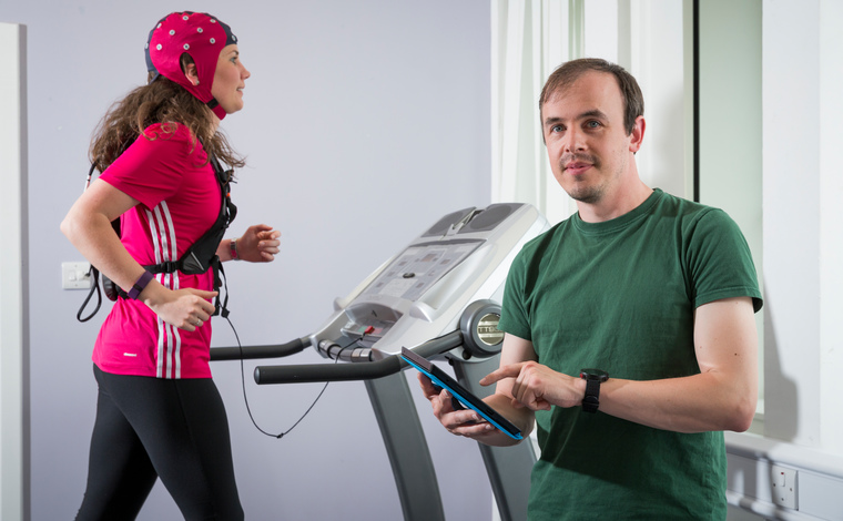 Man with clipboard and woman on running machine