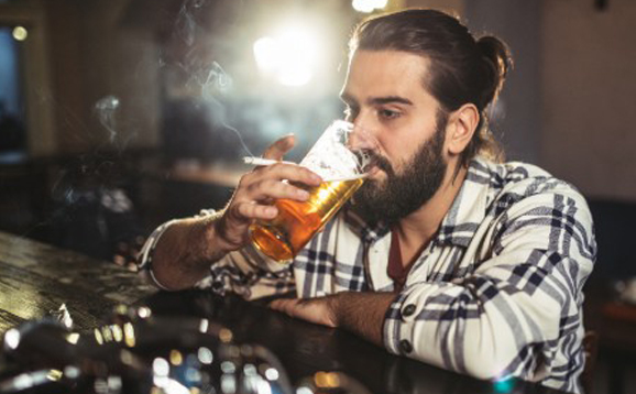 man drinking beer and smoking
