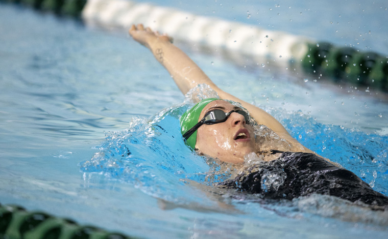 Student wearing goggles and swimming backstroke