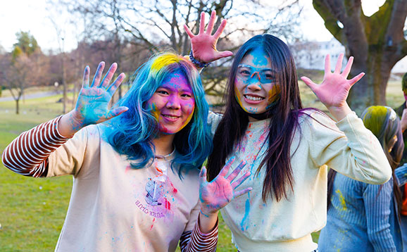 A pair of happy students covered in brightly coloured paint powder