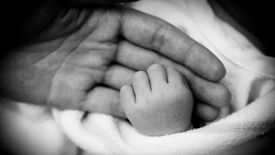A new dad holds his baby's hand