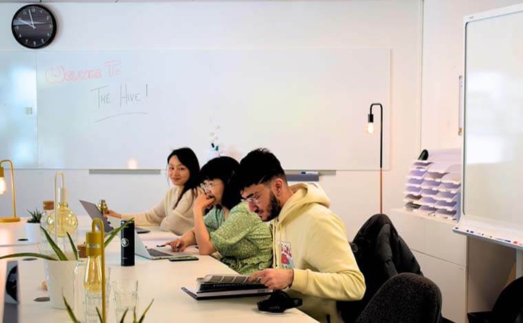 Three students working at a desk in a hub