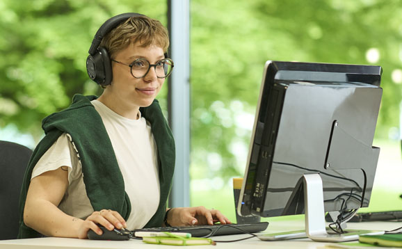 student wearing headphones and using a computer