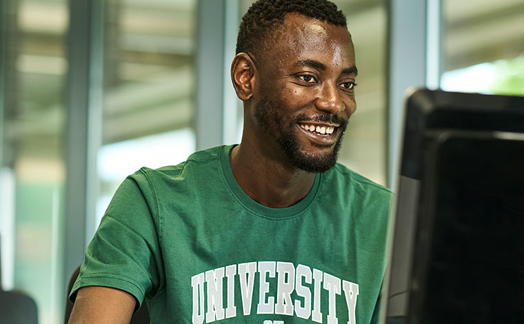 A student with a University of Stirling tshirt working at a desktop computer