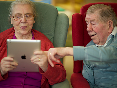 Two older people use dementia app on tablet