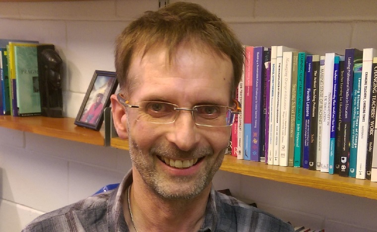 Head shot of Mark Priestley in front of book shelves