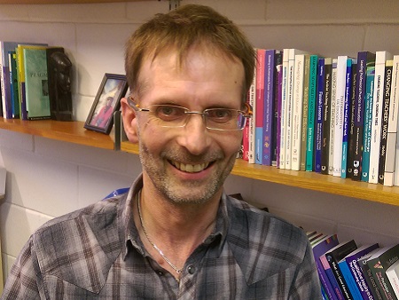 Head shot of Mark Priestley in front of book shelves