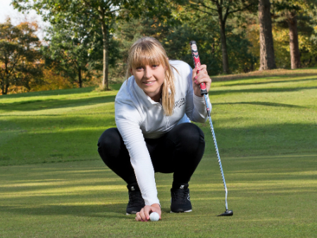 Nicola Slater crouching down, lining up a putt on golf green