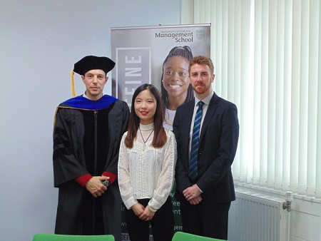 Academic in graduate robes with Chinese woman and German man