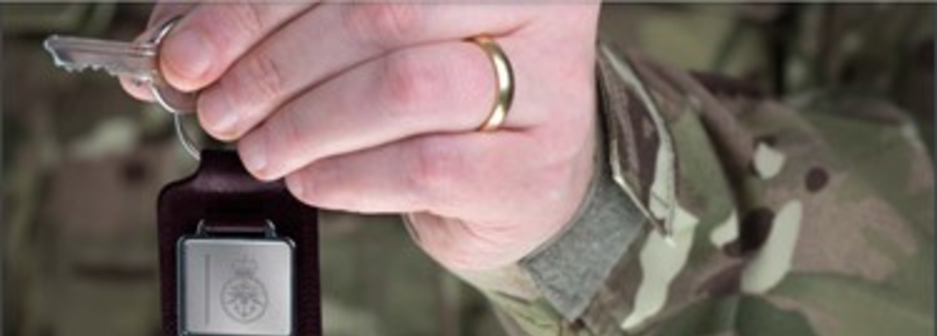 Hand of person in military uniform holding a key up