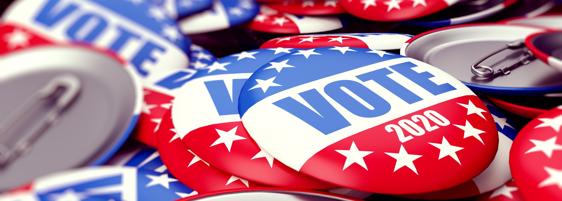 A pile of badges with the US flag on them and the words VOTE 2020