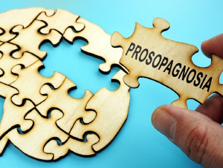 A jigsaw piece labelled 'prosopagnosia' being placed into a jigsaw of the human brain.