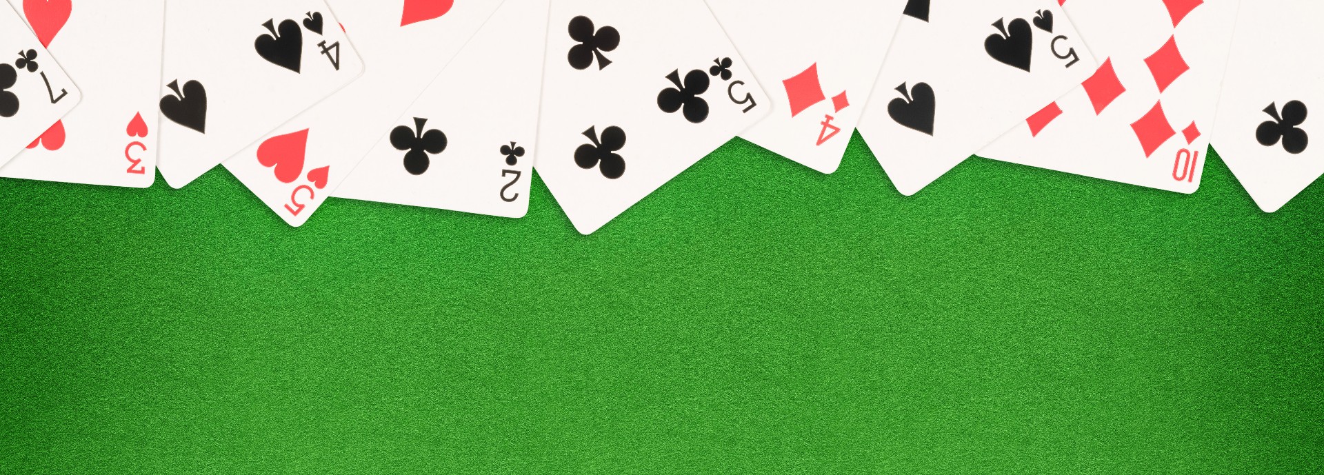 Playing cards spread out on a green felt background