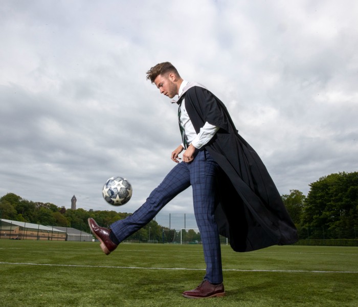 Footballer Craig Brown performs keepie-uppies in his graduation gown