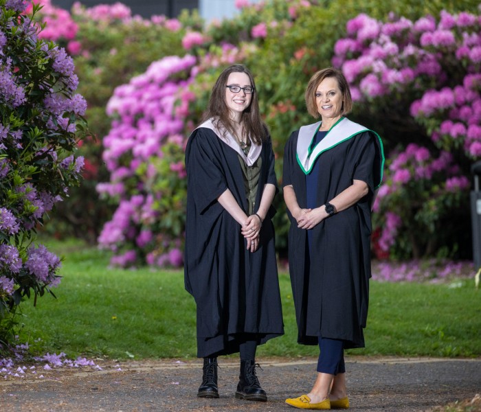 Vicki and Hannah Lawlor wear university graduations gowns and pose on the Stirling campus