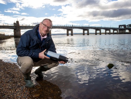 Prof Andrew Tyler holding a sensor by the Kincardine Bridge