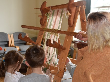 Children at heritage museum looking at weaving