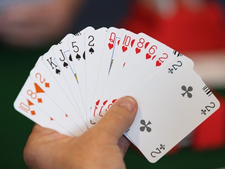 Hand holds up a deck of cards in a fan shape to camera