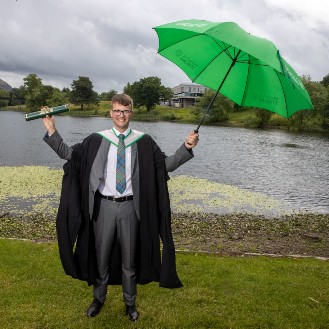 University graduate with green umbrella