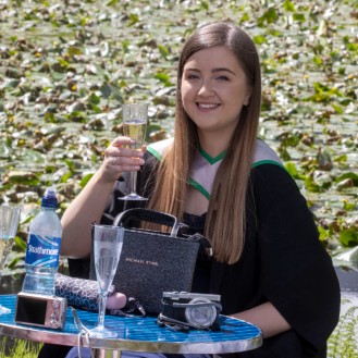 Graduate enjoys a glass of champagne at the graduation garden party