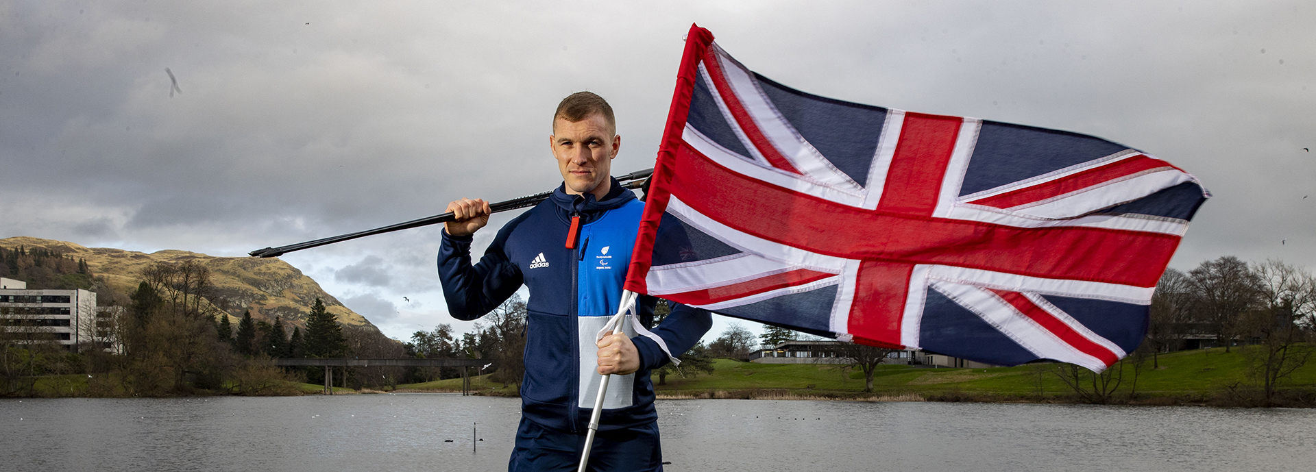 Scott Meenagh with GB flag and ski poles