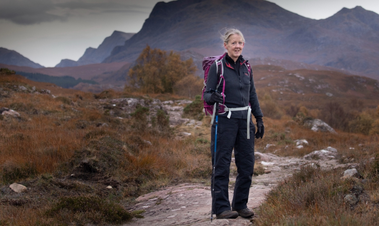 Helen Davies in hiking gear posing against a mountainous backdrop