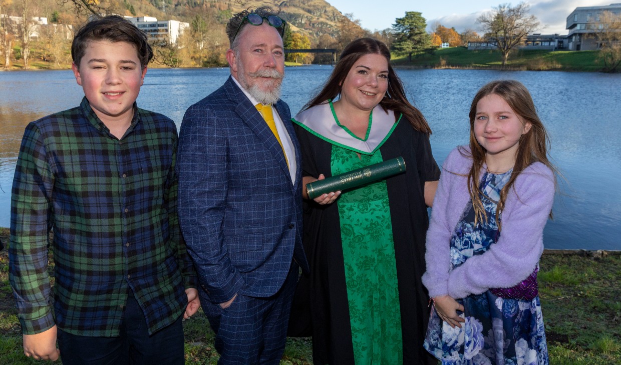 Suzie John poses with her son, daughter and husband next to the loch on campus