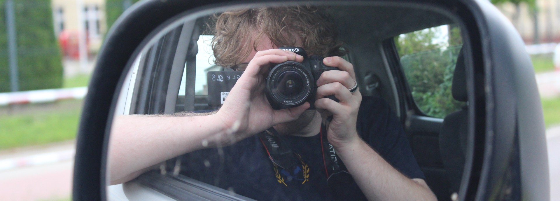 Kai takes a photo of himself in the wing mirror