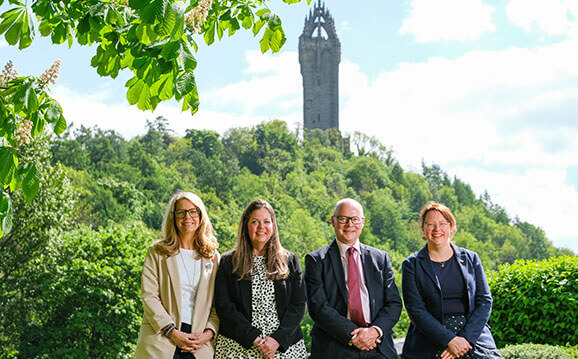University staff pose with Wallace Monument in background