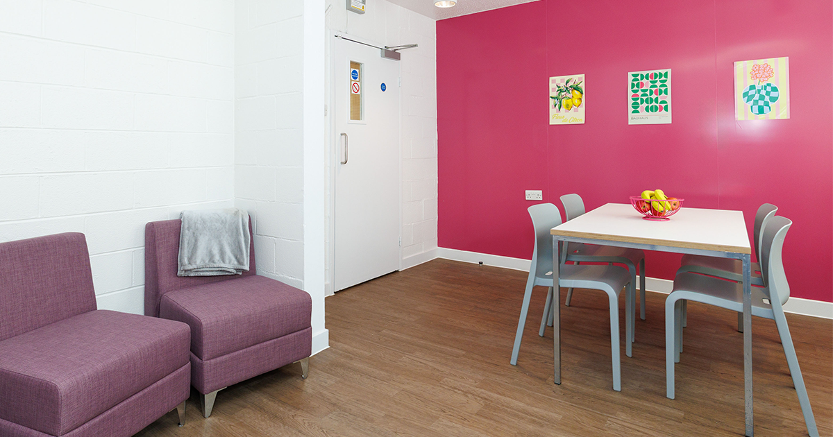Photo of shared space in H H Donnelly House student accommodation. Showing table, chairs and some comfy seats.