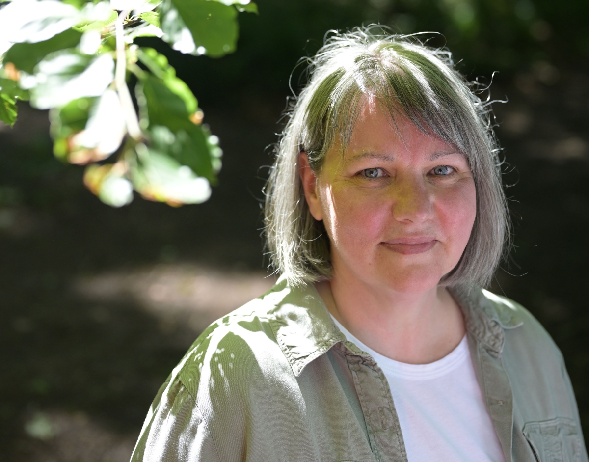 Woman looking at camera with leaves in background