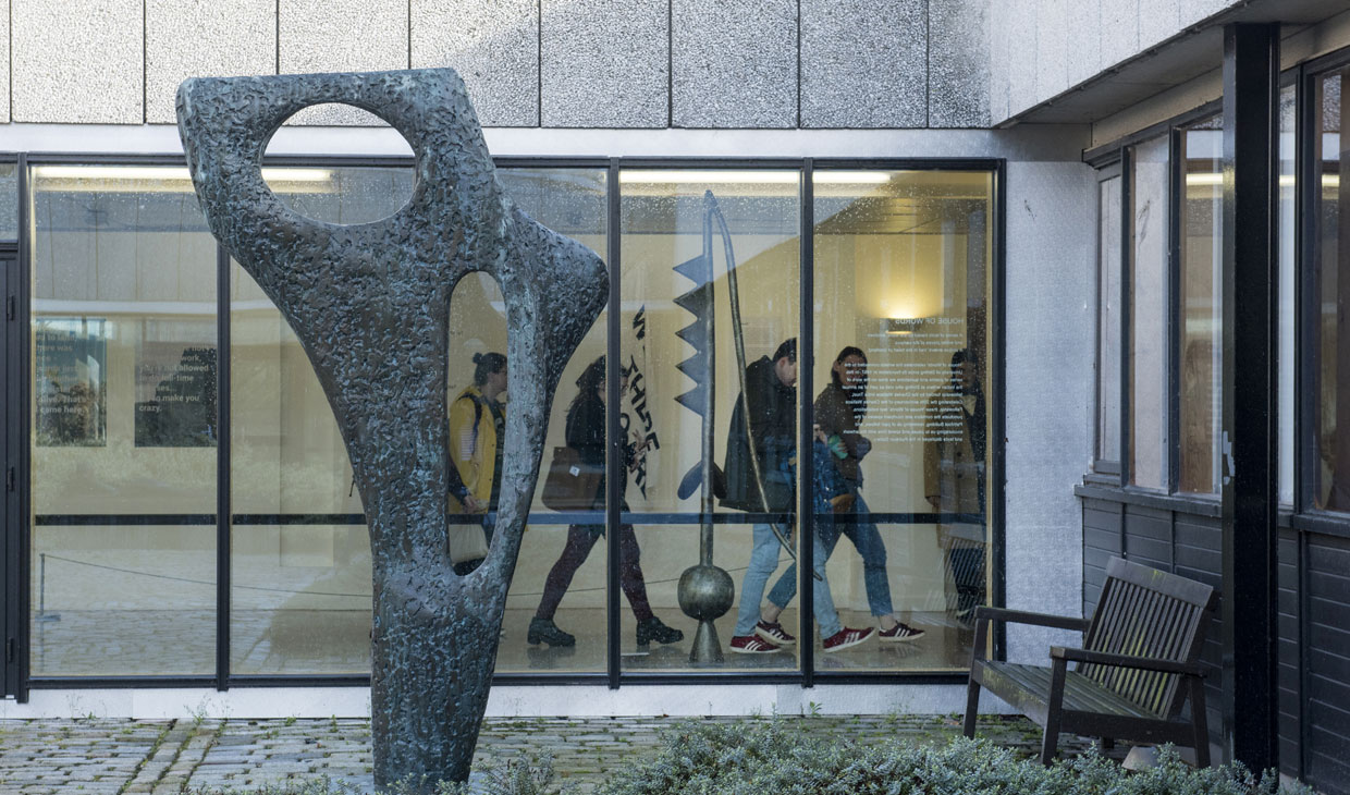 Grey sculpture outside, with students walking past
