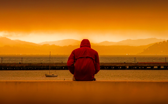 person sitting on wall at sunset