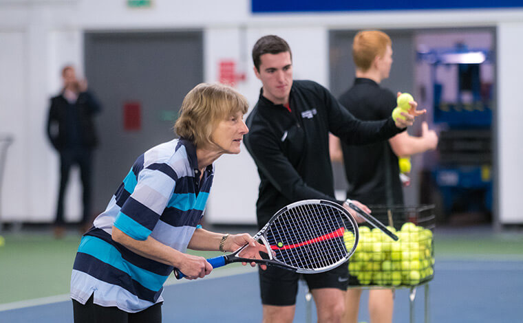 Adult getting a tennis lesson from a coach