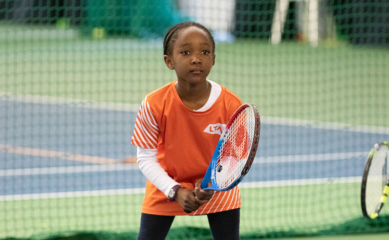 Child playing tennis on court